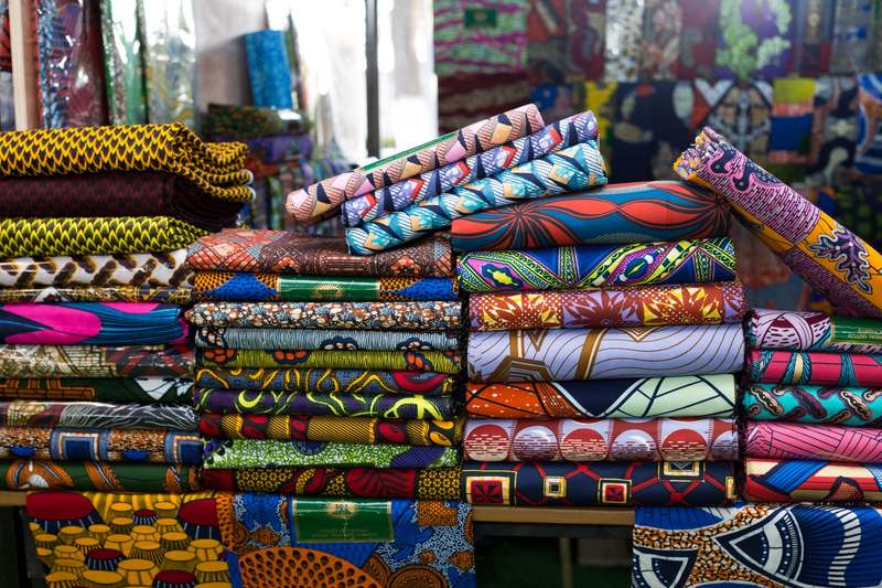 Piles de pagnes wax aux motifs colorés sur un étal