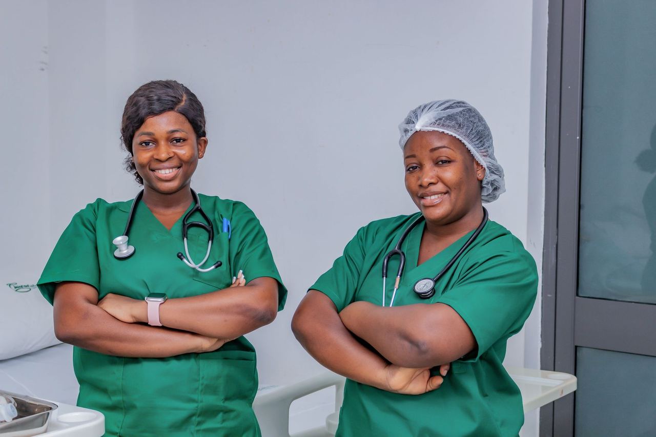 Deux infirmières en tenue verte, souriantes, dans une salle de soins