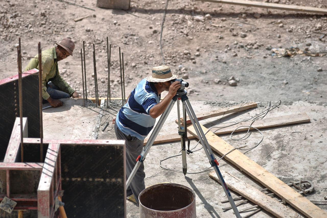 Techniciens réglant un appareil de mesure topographique sur un chantier ensoleillé