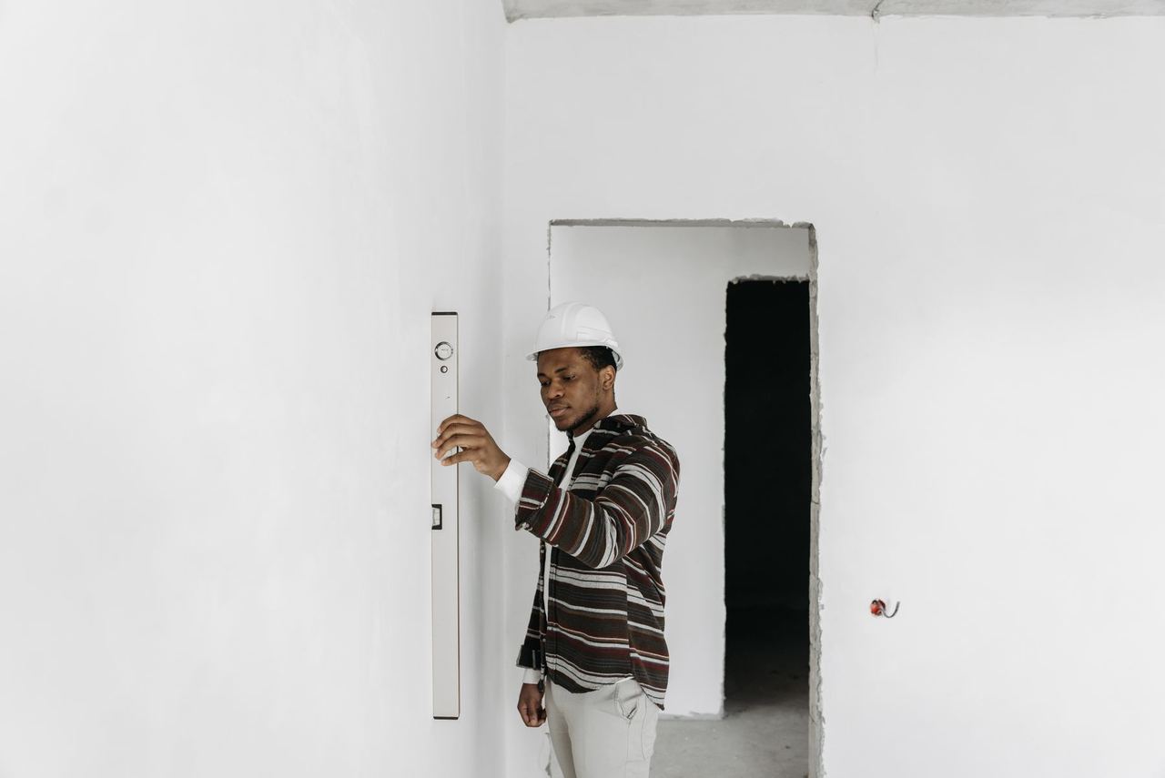Artisan vérifiant l'aplomb d'un mur fraîchement enduit à l'aide d'un niveau
