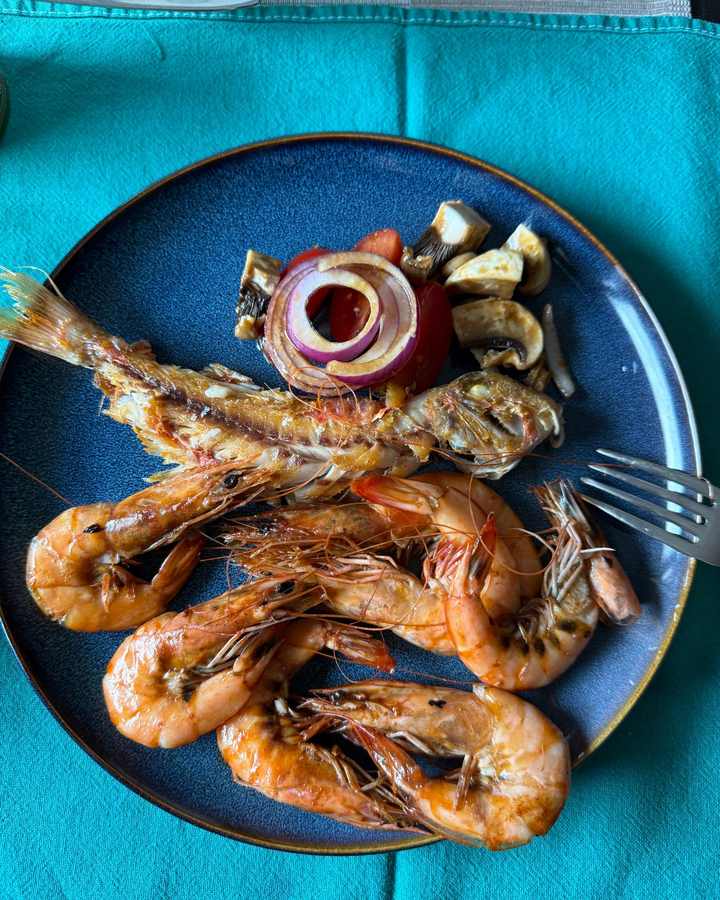 Assiette de crevettes et de poisson grillés avec légumes, sur une nappe turquoise