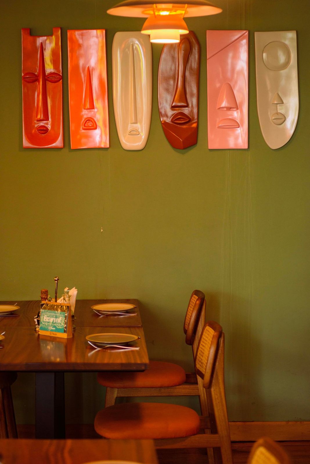 Salle de restaurant chaleureuse aux murs verts décorés de masques en bois