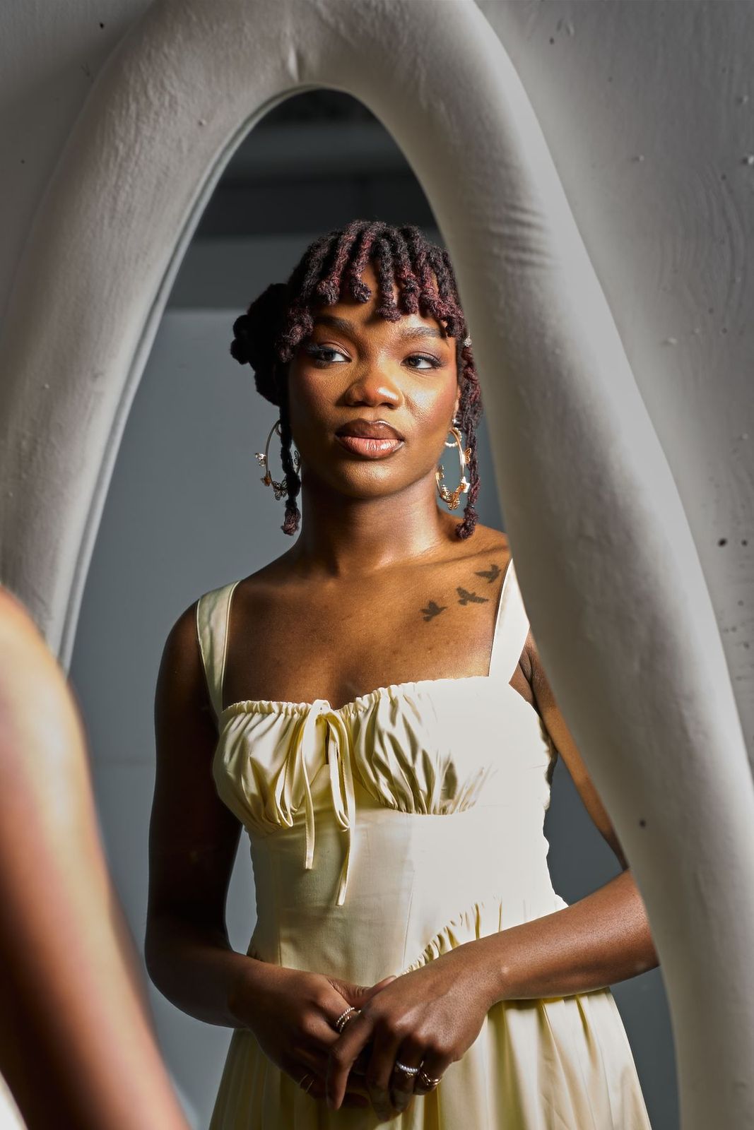 Femme en robe jaune aux cheveux naturels, reflétée dans un miroir en arche