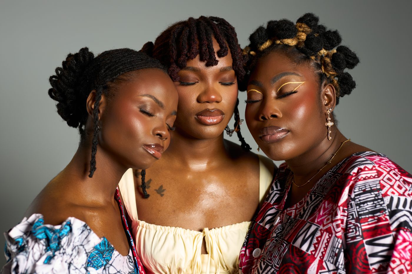 Trois femmes aux coiffures naturelles vêtues de tissus imprimés